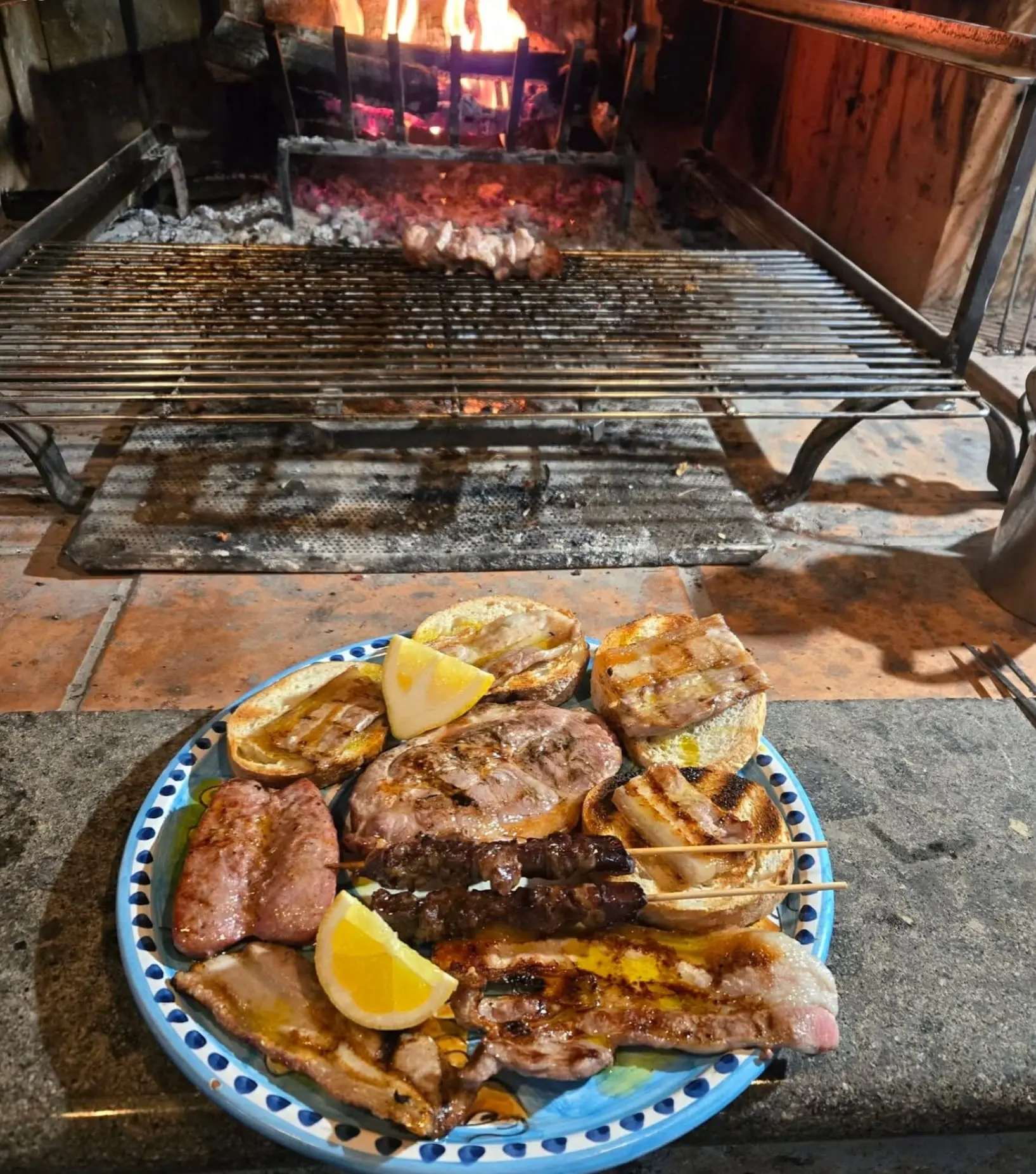 Piatto di grigliata mista con bruschette e limone davanti al camino